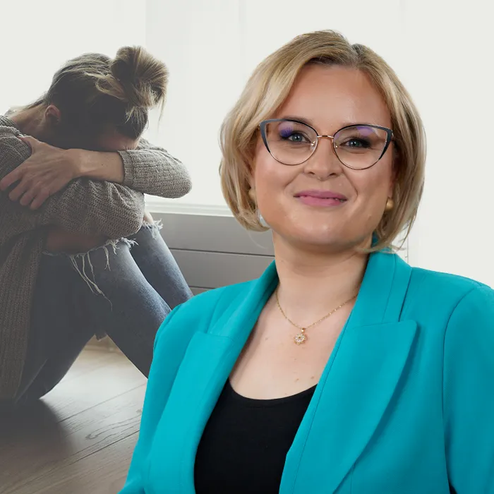 Kobieta w turkusowej marynarce uśmiecha się pewnie na pierwszym planie, podczas gdy inna kobieta siedzi w tle, obejmując kolana i wyglądając na przygnębioną.